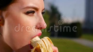 在阳光明媚的日子里，动作缓慢、身材迷人、有着美丽眼睛和红唇的年轻<strong>黑</strong>发女人吃香蕉